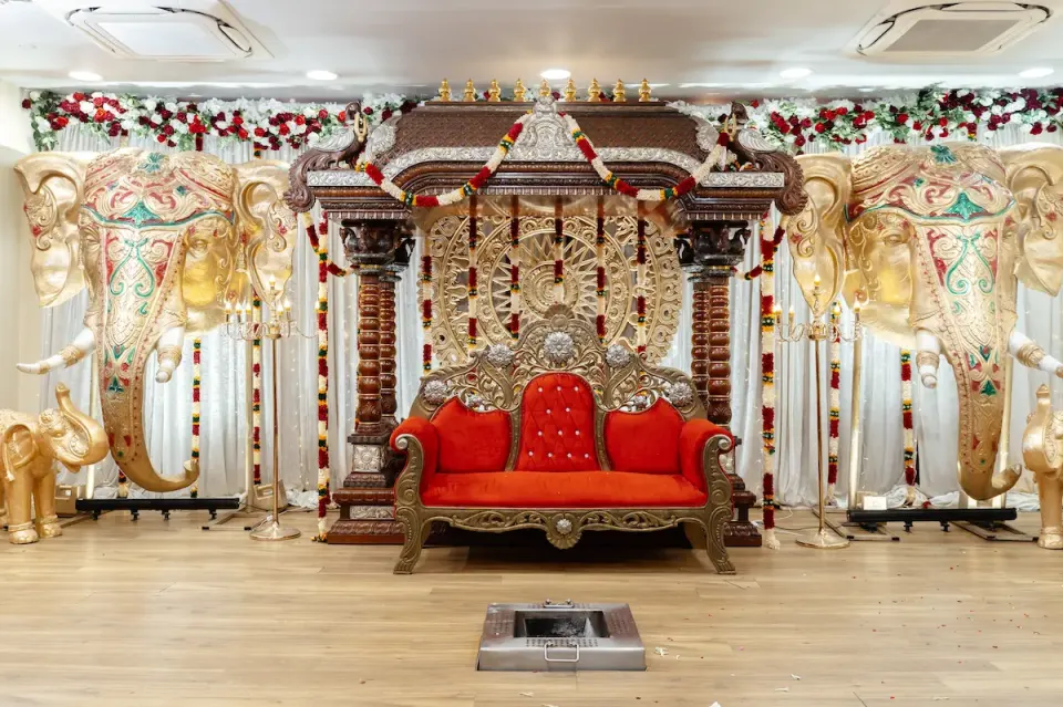 Carved gold mandap with red sofa